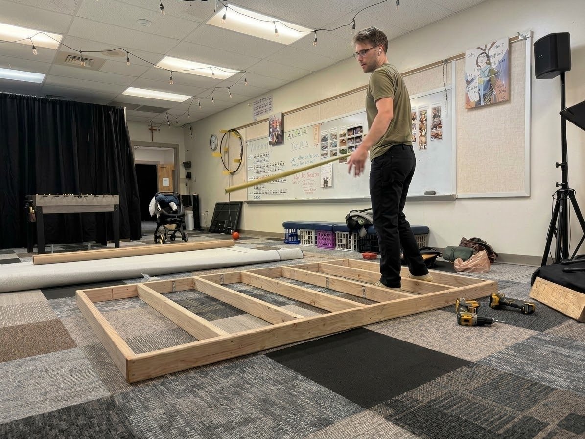 Dillon measuring a framed 2x4 wall section laid out on the floor